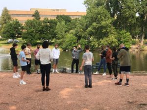 group of students standing at pond